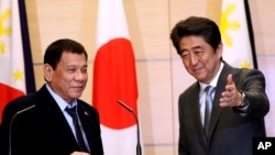 Philippine President Rodrigo Duterte, left, is shown the way by Japanese Prime Minister Shinzo Abe after a joint press conference following their meeting at Abe's official residence in Tokyo, Oct. 26, 2016.