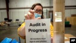 A Chatham County election official posts a sign in the public viewing area before the start of a ballot audit, Nov. 13, 2020, in Savannah, Ga. 