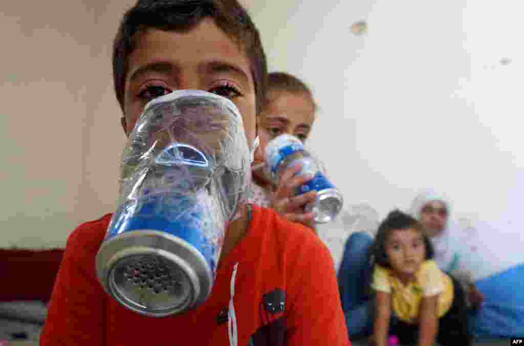 Children try out their improvised gas masks at their home in Binnish in Syria's rebel-held northern Idlib province as part of preparations for any upcoming raids.