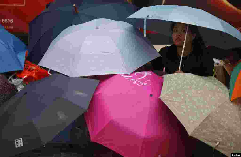 Manifestantes sentam-se cobertos de chapéus-de-chuva na principal rua do centro financeiro distrito às portas da sede do Governo em Hong Kong, Set. 30, 2014. 