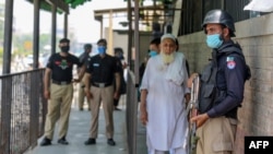 Security personnel, left and right, stand outside the district court building following the killing of a man allegedly accused of blasphemy in Peshawar on July 29, 2020.