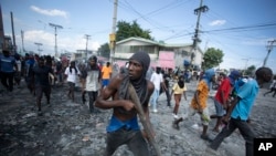 Seorang warga membawa kayu sebagai senjata dalam aksi protes yang menuntut pengunduran diri Perdana Menteri Haiti Ariel Henry di Port-au-Prince, Haiti, pada 3 Oktober 2022. (Foto: AP/Odelyn Joseph)