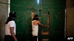 Masked Palestinians secure the door of Jerusalem's Al-Aqsa Mosque, one of Islam's holiest sites, as they plan to remain inside to protect it in case of clashes, Sept. 27, 2015.