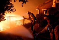 Los Angeles City firefighters battle the Saddleridge fire near homes in Sylmar, Calif., Oct. 10, 2019.