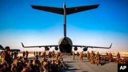 FILE - Marines assigned to the 24th Marine Expeditionary Unit await a flight to Kabul, Afghanistan, at Al Udeied Air Base, Qatar, Aug. 17, 2021. 