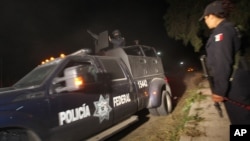 Police agent stands guard as Mexican Federal Police vehicle leaves village of Hueypoxtla, Dec. 4, 2013.