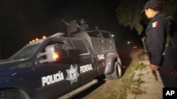 Police agent stands guard as Mexican Federal Police vehicle leaves village of Hueypoxtla, Dec. 4, 2013.