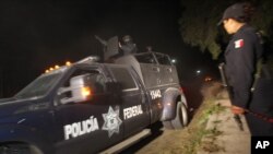 Police agent stands guard as Mexican Federal Police vehicle leaves village of Hueypoxtla, Dec. 4, 2013.