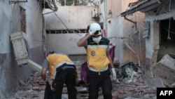 Members of Syria's civil defense service sift through the rubble at al-Shifaa Hospital following shelling of the rebel-held city of Afrin in northern Syria, June 12, 2021. 