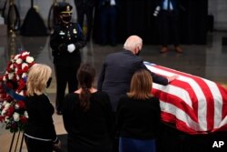 El candidato presidencial demócrata y exvicepresidente de EE.UU., Joe Biden, junto a su esposa Jill Biden, toca el ataúd del fallecido ícono de los derechos civiles John Lewis, en el capitolio en Washington, el lunes 27 de julio de 2020.