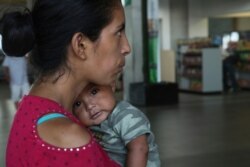 FILE - A woman and her 7-month-old baby stand on a sidewalk after being bused by Mexican authorities from Nuevo Laredo to Monterrey, Mexico.