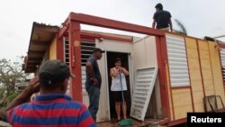 Des familles nettoient ce qui reste de leurs maisons après le passage de l’ouragan Maria à Toa Baja, Porto Rico, 18 octobre 2017.