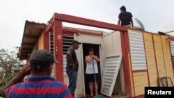 Des familles nettoient ce qui reste de leurs maisons après le passage de l’ouragan Maria à Toa Baja, Porto Rico, 18 octobre 2017.