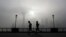 FILE - People jog past the Pudong Financial District shrouded with fog and pollution at the Shanghai Bund in Shanghai, China,  April 14, 2016. 