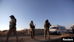 FILE - An ambulance passes by Islamist rebels from Hayat Tahrir al-Sham outside the villages of al-Foua and Kefraya,Syria July 18, 2018. 