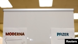 FILE - Signs and age groups are shown for the Pfizer and Moderna vaccines at a vaccination center in Chula Vista, California, Apr. 15, 2021.