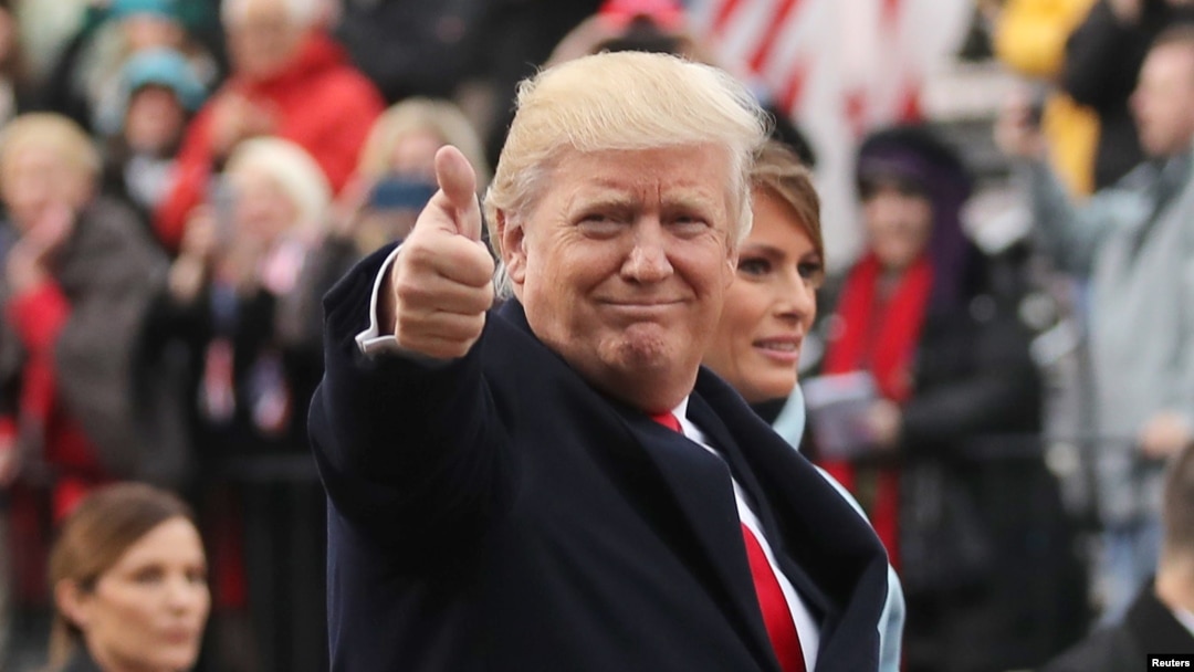 U.S. President Donald Trump points to the stands as he walks with his wife Melania during the Inaugural Parade in Washington, Jan. 20, 2017. 