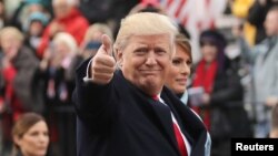 U.S. President Donald Trump points to the stands as he walks with his wife Melania during the Inaugural Parade in Washington, Jan. 20, 2017. 