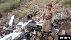 A man points as he stands in the site of the wreckage of a U.S. MQ-9 drone that Houthis claim they shot out of the sky, in a location given as Saada Governorate, Yemen, in this undated screengrab taken from a video obtained by Reuters Aug. 4, 2024. 