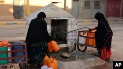 FILE - Moroccan women filling up containers with water from a hose, in Zagora, southeastern Morocco, Oct. 19, 2017. Experts blame poor choices in agriculture, growing populations and climate change for the water shortages in towns like Zagora. Moroccan state TV channel 2M reports that at least 15 people have died and 5 others have been injured in a stampede on Nov. 19, 2017 as food aid was being distributed in the village of Sidi Boulalam. 