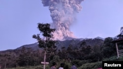 Beberapa wisatawan memperhatikan Gunung Merapi yang sedang erupsi, di Cangkringan, Sleman, Yogyakarta, 3 Maret 2020, sebagai ilustrasi. (Foto: Antara via Reuters)