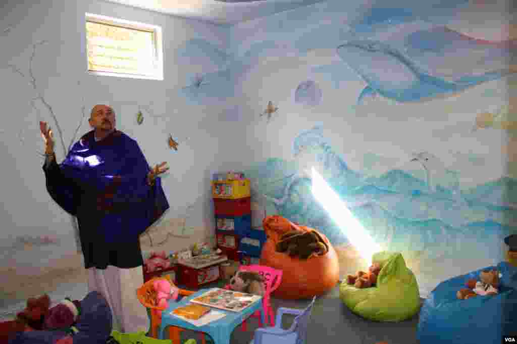 Hospice psychologist Cameron Hogg shows off murals in a pastel-filled Wits Hospice playroom. Opposing walls are filled with African elephants lumbering toward a burnt-orange sunset. (Photo by Darren Taylor) &nbsp;