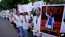 Médicos e estudantes de medicina seguram cartazes e velas durante um protesto contra a violação e morte de um médico estagiário num hospital público em Calcutá na semana passada, em Ahmedabad, Índia, sábado, 17 de agosto de 2024.