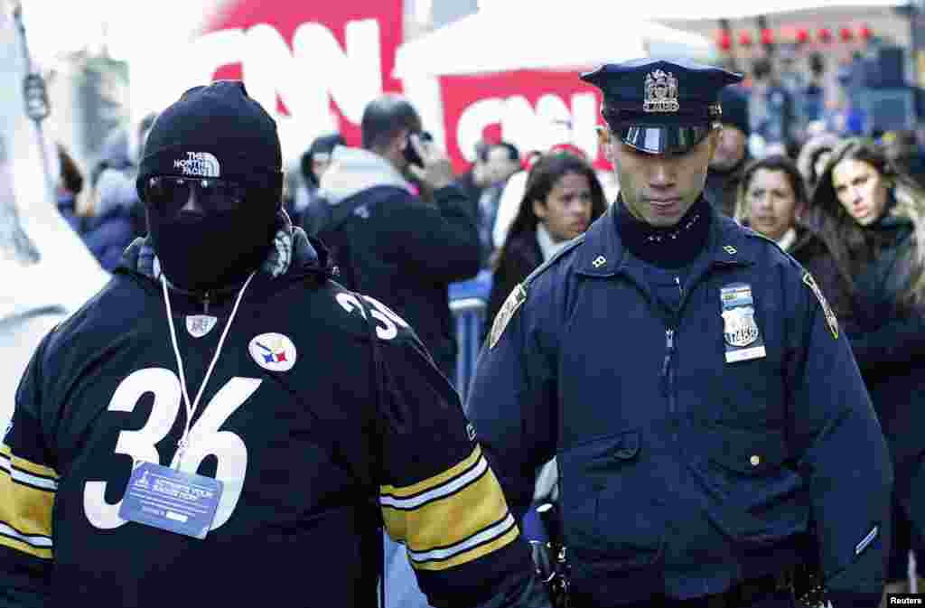 A police officer walks next to a fan at the Super Bowl Boulevard fan zone ahead of Super Bowl XLVIII in New York, Jan. 30, 2014. 