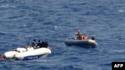 Des marins de l'USNS Trenton vont au secours des gens d'un canot en caoutchouc renversé, à gauche, dans la mer Méditerranée, le 12 juin 2018.