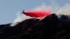 A firefighting plane makes a retardant drop on a hill near a wildfire in Azusa, Calif., June 20, 2016.