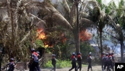 Policemen walk towards burning buildings in Sittwe, capital of Rakhine state in western Burma, where sectarian violence is ongoing, June 12, 2012. 