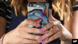 Rachel Whalen looks at her phone at her home in Draper, Utah, July 22, 2019. Whalen remembers feeling gutted in high school when a former friend would mock her online postings and post inside jokes about her to others online.