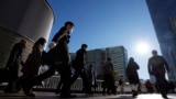 FILE - Commuters walk in a passageway during a rush hour at Shinagawa Station, Feb. 14, 2024, in Tokyo. 