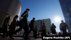 FILE - Commuters walk in a passageway during a rush hour at Shinagawa Station, Feb. 14, 2024, in Tokyo. (AP Photo/Eugene Hoshiko, File)