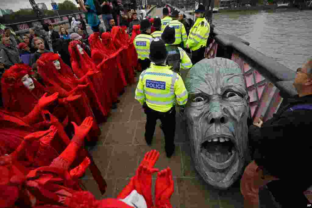 Environmental protesters gather around the head of a statue confiscated by police on Lambeth bridge in central London.