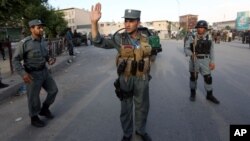 FILE - Afghan security forces stand guard at site of suicide car bombing attack in Kabul, May 19, 2015.