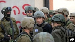 FILE - Israeli Prime Minister Benjamin Netanyahu, center, wears a protective vest and helmet as he receives a security briefing with commanders and soldiers in the northern Gaza Strip, on December 25, 2023.