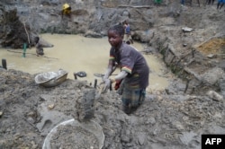 FILE - A child gold miner works in a traditional gold mine in the village of Gam, May 5, 2014.