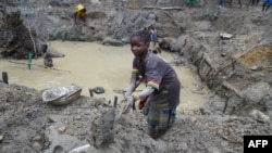 (FILE) A child gold miner works on May 5, 2014 while looking for gold in a traditional mine in the village of Gam, where gold mining in the main business activity of the region.