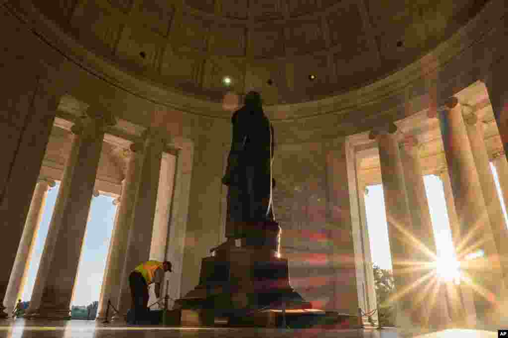 A U.S. Park Service employee dusts off the statute of Thomas Jefferson as the sun streaks through the pillars at the Jefferson Memorial in Washington, D.C., early in the morning,. The temperature was expected to reach the 90s (F) in the nation&#39;s capital.