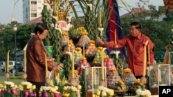 Cambodian Prime Minister Hun Sen, right, sprays perfume together with Deputy Prime Minister Sok An during a ground breaking ceremony for the site where a statue of Cambodia's late King Norodom Sihanouk will be built, in front of Independence Monument in Phnom Penh, Cambodia, Wednesday, Feb 20, 2013. 