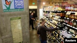 FILE - Employees stock shelves near a sign supporting non genetically modified food at the Central Co-op in Seattle, Washington October 29, 2013.