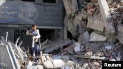 A Houthi militant carries computer components out of the Chamber of Trade and Industry headquarters after it was hit by a Saudi-led air strike in Yemen's capital, Sana'a, Jan. 5, 2016.