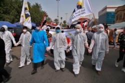 Anti-government protesters wear hazmat suits and gas masks during a rally demanding women's rights during the International Women's Day in Tahrir square in Baghdad, Iraq, March 8, 2020.