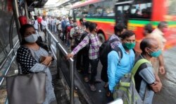 Orang-orang yang memakai masker do tengah pandemi COVID-19, menunggu di halte bus di Mumbai, India, Senin, 7 Juni 2021.