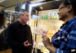 Adam Smith, left, founder and executive director of Oregon Craft Cannabis Alliance, is shown a variety of edible marijuana products by Tree PDX marijuana shop owner Brooke Smith at her shop in Portland, Ore.