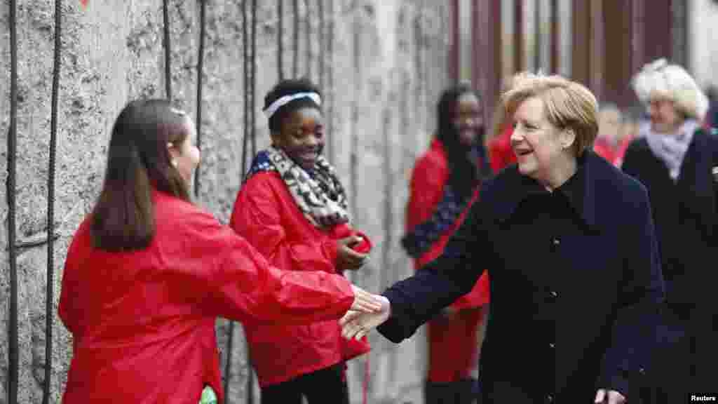 La chancelière allemande Angela Merkel serre la main avec les enfants symbolisant les gens qui ont ébréché le mur avec des marteaux, à la commémoration du 25ème anniversaire de la chute du mur de Berlin à Bernauer Strasse, Berlin, le 9 novembre 2014.
