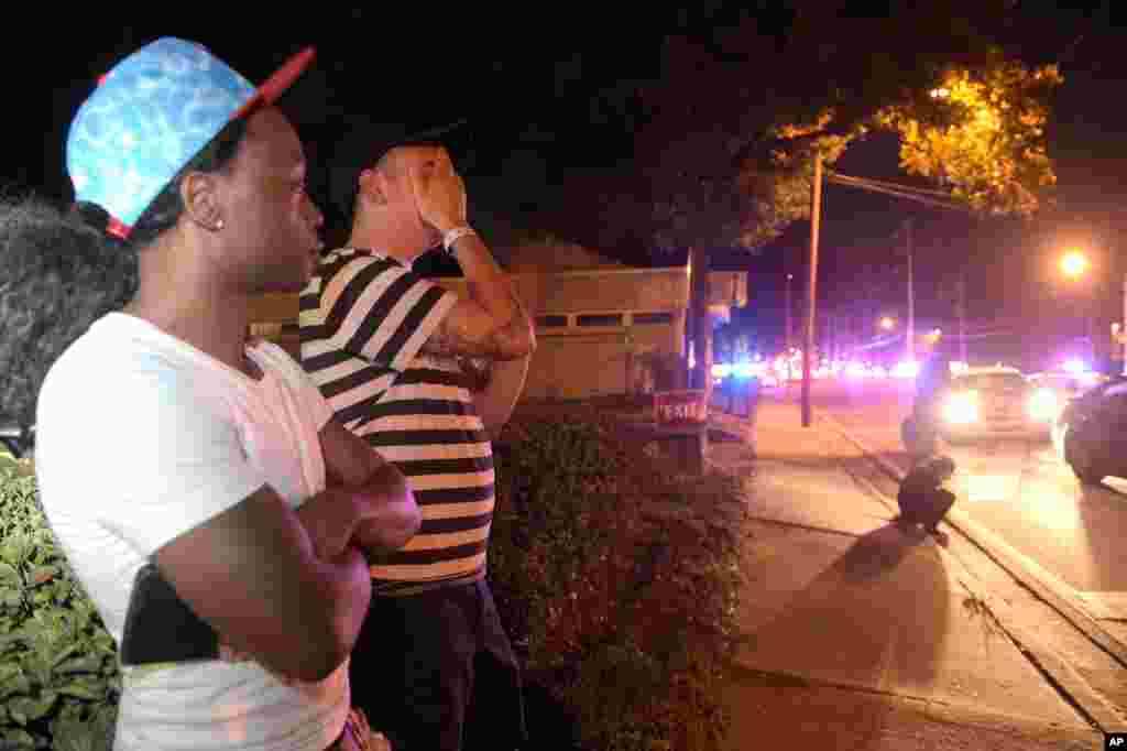 Jermaine Towns, left, and Brandon Shuford wait down the street from a multiple shooting at a nightclub in Orlando, Fla., Sunday, June 12, 2016. Towns said his brother was in the club at the time. (AP Photo/Phelan M. Ebenhack)