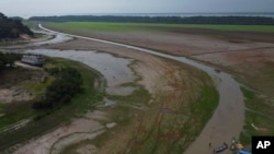 FILE - Fishermen push a boat in the Aleixo Lake during a drought in Manaus, Amazonas state, Brazil, Sept. 24, 2024.