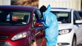 A medical technician performs a nasal swab test on a motorist at a COVID-19 testing site near All City Stadium, Dec. 30, 2021, in Denver. With the rapid spread of the omicron variant paired with the Christmas holiday, testing sites have been strained to m